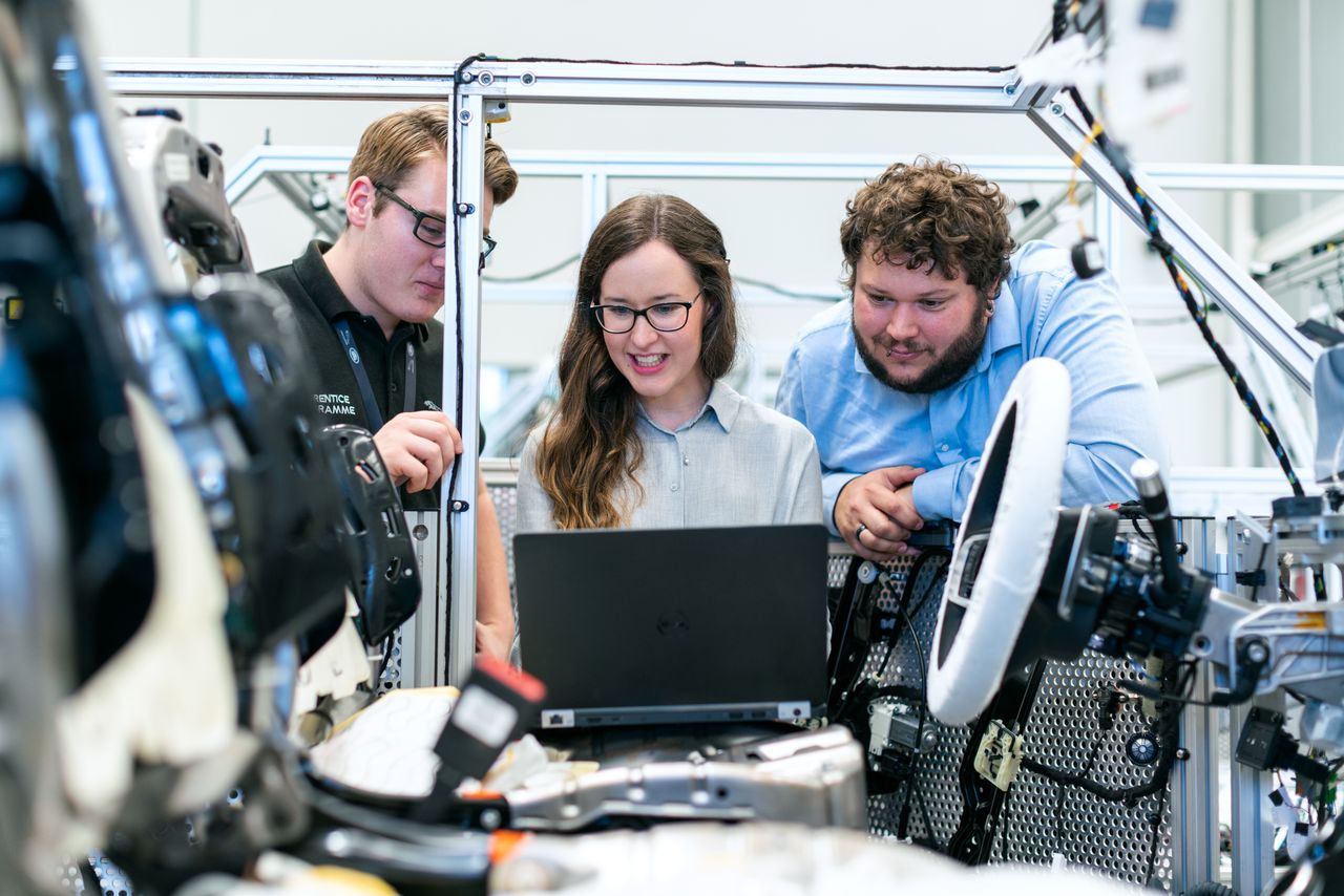 Automotive engineers collaborating on a vehicle technology project in a real workshop