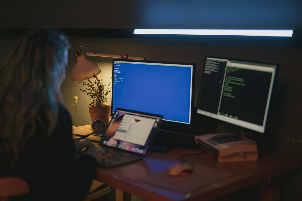 Cybersecurity specialist working across multiple computer screens in a real office environment