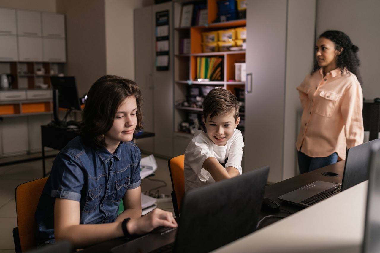 Teacher supporting students who are using laptops in a real learning environment