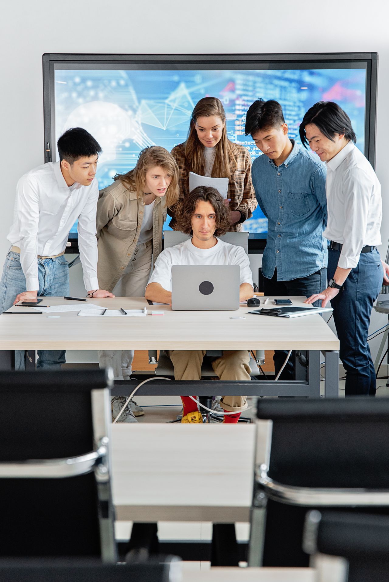 Diverse professional technology team collaborating around a laptop in a real office