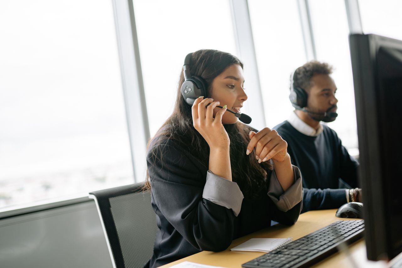 Professional support team working with computers and headsets in a real office